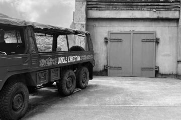 black and white photo of a vehicle parked by a gate