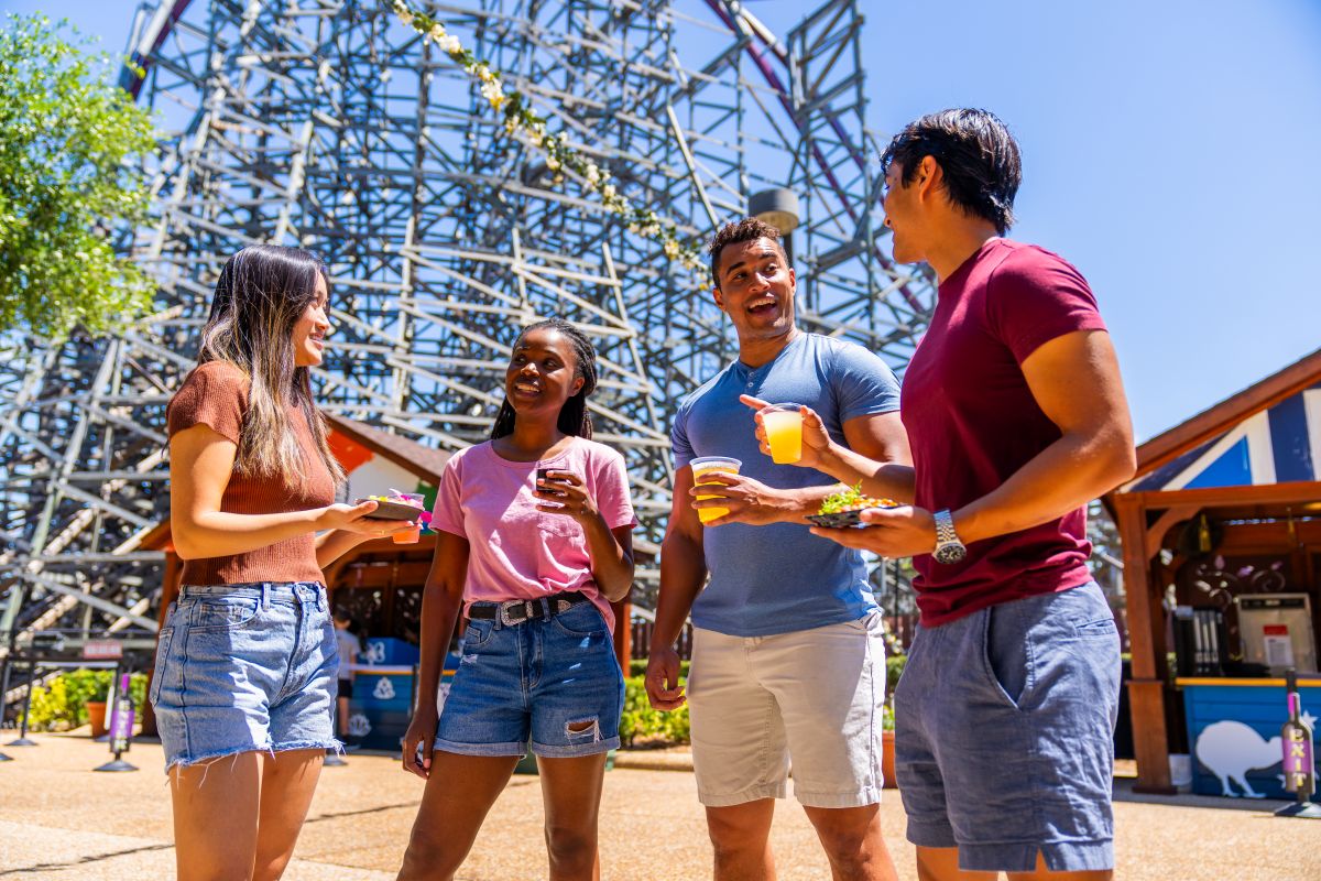 Florida Platinum Pass reasons to buy- photo showing people enjoying a beverage in front of a roller coaster