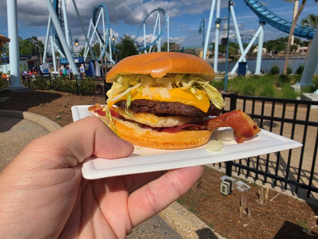 Breakfast Burger Review photo showing a burger being held up with a roller coaster in the background