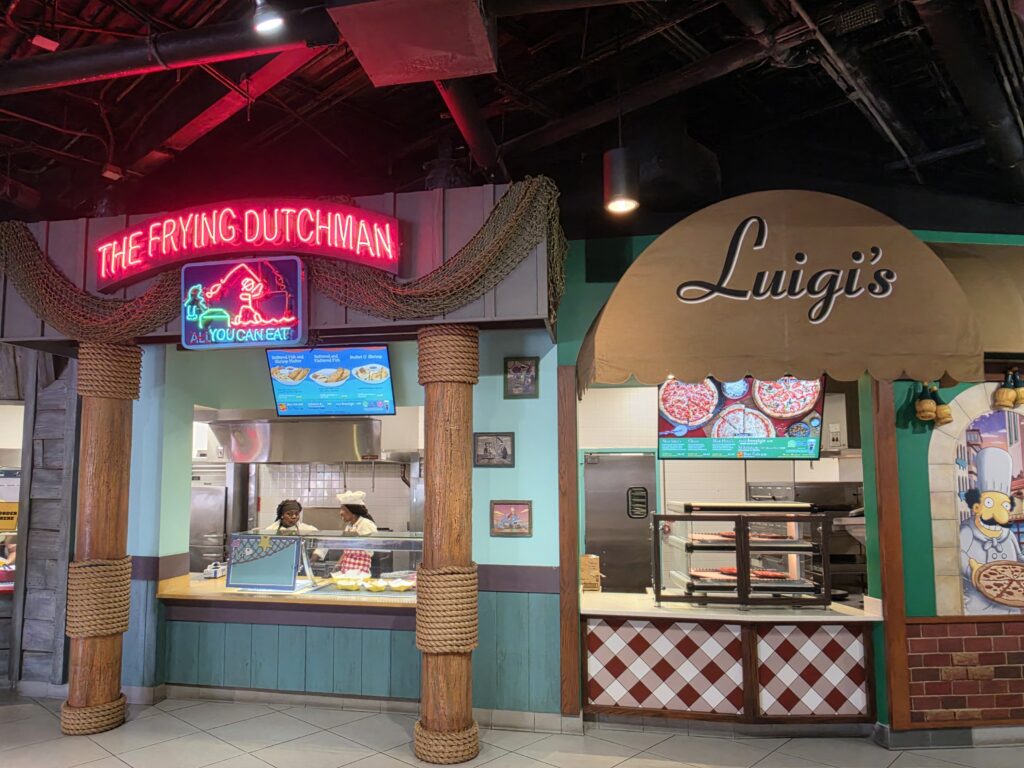 Interior of a themed restaurant with a neon sign reading 'The Frying Dutchman' near a counter in view of staff behind it.