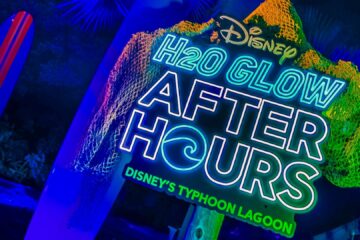Neon sign for Disney H2O Glow Aqua Tours at Typhoon Lagoon and water park backdrop.