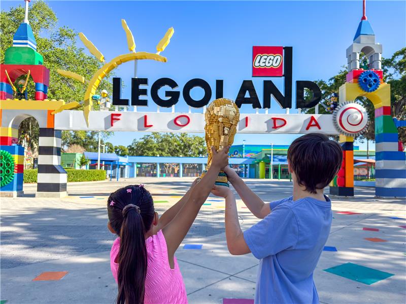 Promotional photo for Legoland FIFA World Cup showing kids holding up the FIFA trophy
