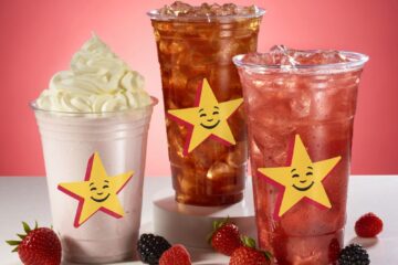 Three star-decorated cold drinks on a white surface: a whipped-cream-topped shake on the left and two berry sodas, against a pink backdrop.