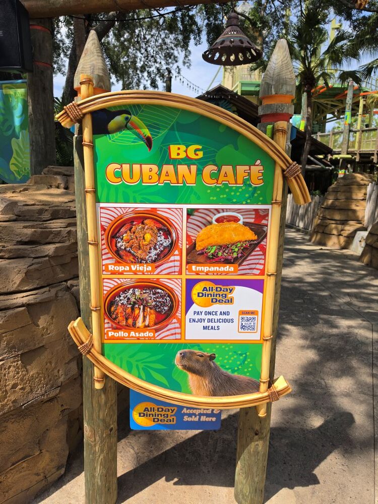 Bright signboard for BG Cuban Café with tropical design and dish photos (Ropa Vieja, Empanada, Pollo Asado) and an All-Day Dining Deal panel.