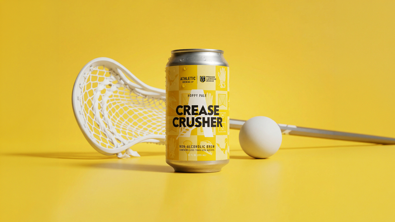 Can of Crease Crusher Brew athletic beverage with lacrosse stick and ball on a bright yellow background (lacrosse-themed product photo).