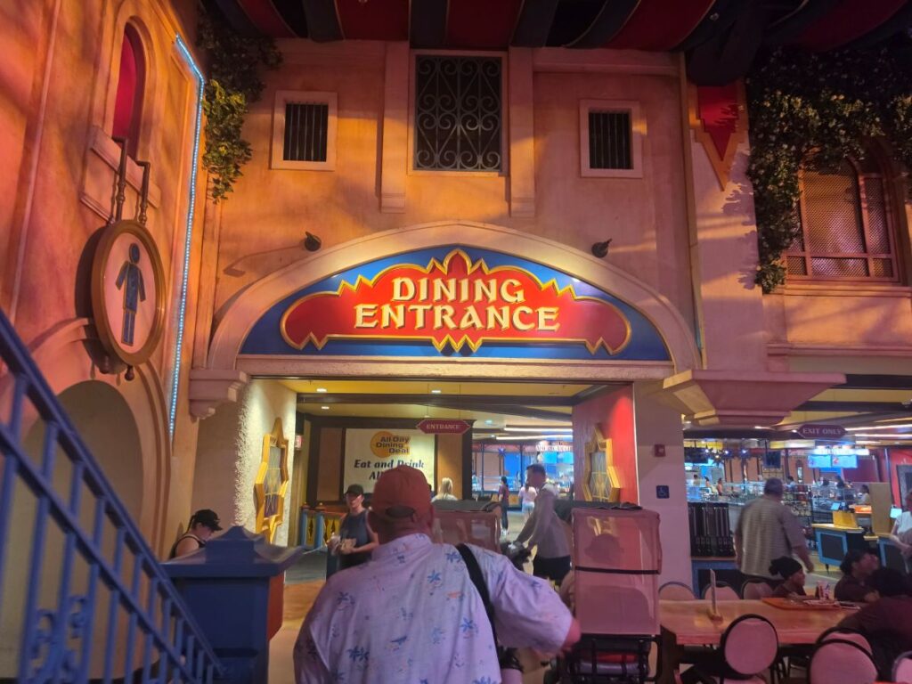 Bright, arched entrance labeled 'DINING ENTRANCE' over a bustling indoor dining area with people seated and walking inside