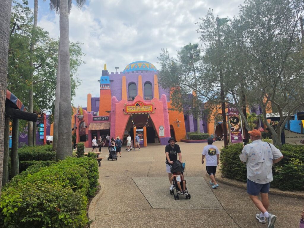 Colorful fantasy-styled entrance with orange and purple walls, central arch, and a dome, in a family-friendly park.