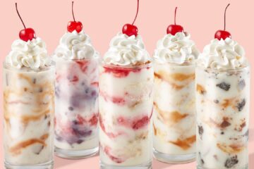 Row of six tall milkshakes topped with whipped cream and a cherry on a peach background, lined up for a dessert banner promoting Freddy's Custard Tour