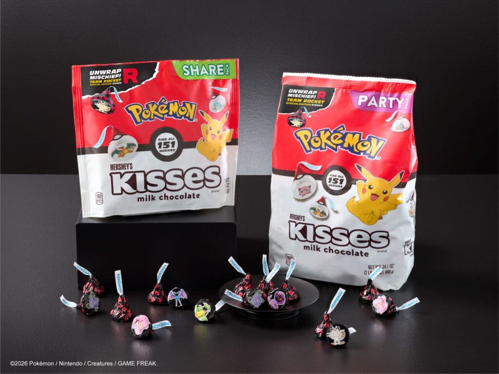 Two Hershey's Pokemon Collection themed kisses bags (milk chocolate) with Pikachu artwork sit on a black backdrop, surrounded by wrapped candies on a dark surface.