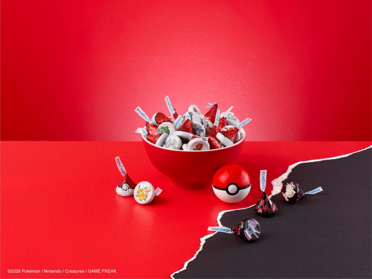 Red bowl overflowing with Pokémon-themed candies wrapped in red foil on a red surface.