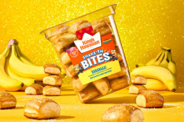Tilted Kings Hawaiian Shake ’N Bites Banana flavor container on a bright yellow glitter backdrop, surrounded by bananas and bite-sized pastries to promote King's Hawaiian Banana Bites