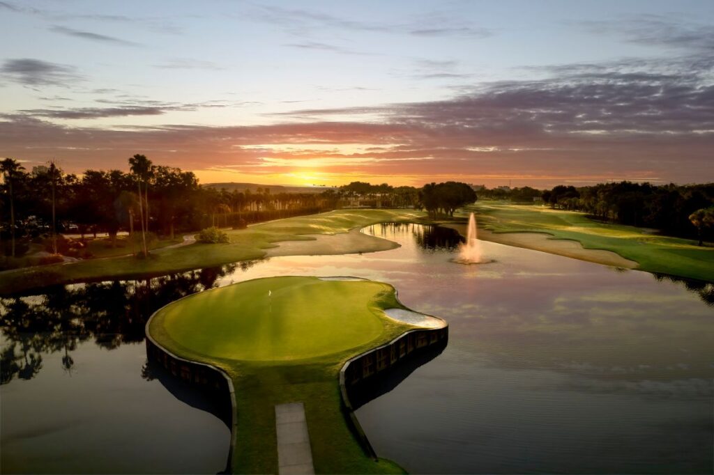Sunset over a golf course with a water hazard and an island green.