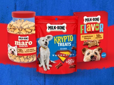 Assorted Milk-Bone Supergirl treats: a jar of morsels, a Krypto treats bag, and a Flavor Snacks bag against a blue and red background.