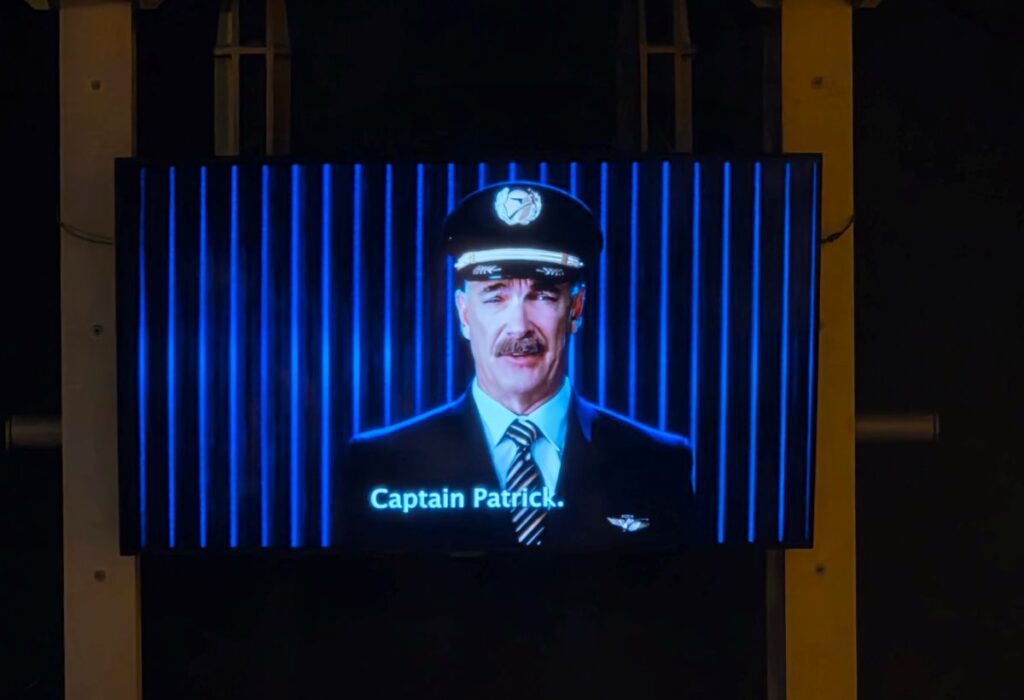 Captain Patrick appears on a blue-lit screen, wearing a pilot's hat and suit with the caption 'Captain Patrick.'