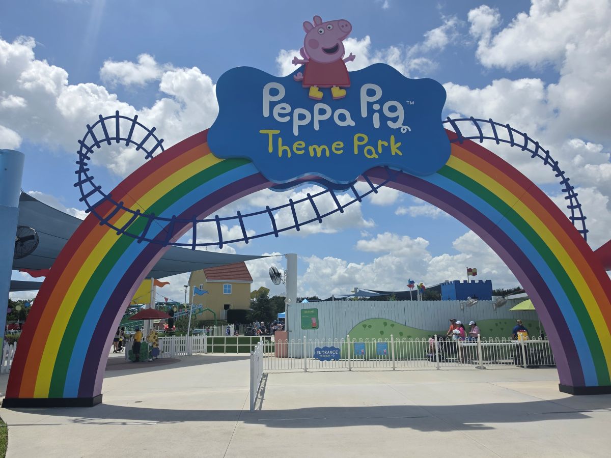 Entrance to Peppa Pig Theme Park with a large rainbow arch and a blue sign featuring Peppa Pig logo.