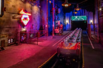 Indoor bumper cars at a neon-lit arcade with a tunnel in the distance.