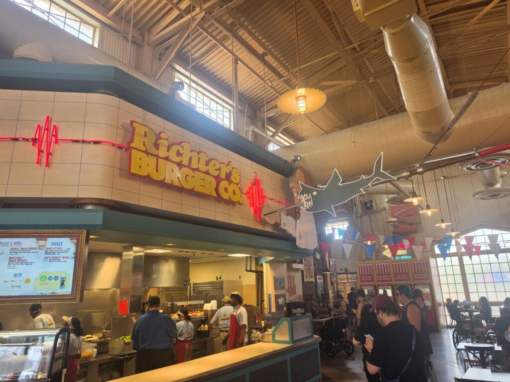 Inside a busy food hall at Richer’s Burger Co with staff cooking and customers ordering.