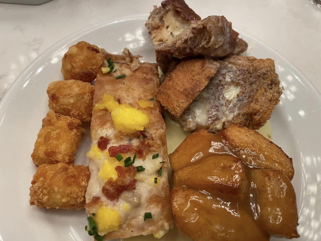 Plate of assorted fried foods: crispy chicken bites, a cheesy battered fish piece, and orange-glazed chunks on a white plate.