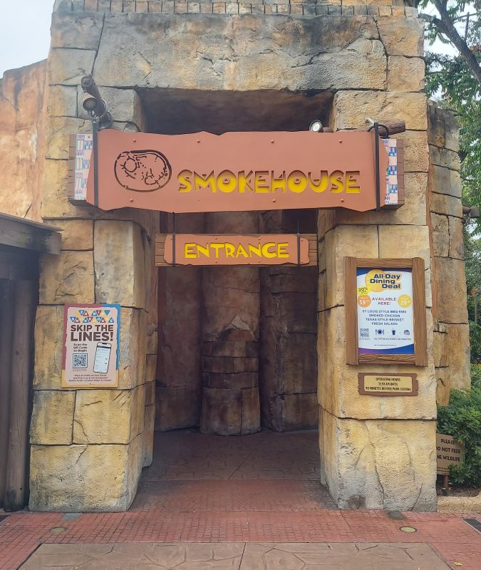 Stone rock façade with an orange SmokEHOUSE sign and a smaller 'Entrance' sign above a tunnel entrance.