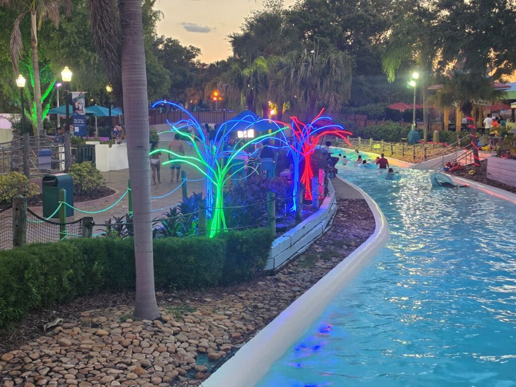 Trees with lights near the lazy river with people flaoting by