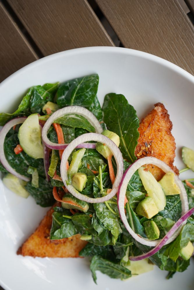 A vibrant crispy rice salad featuring fresh mixed greens, shaved red onions, cucumber, and diced avocado, served as part of the city works chef selects features at Disney Springs.