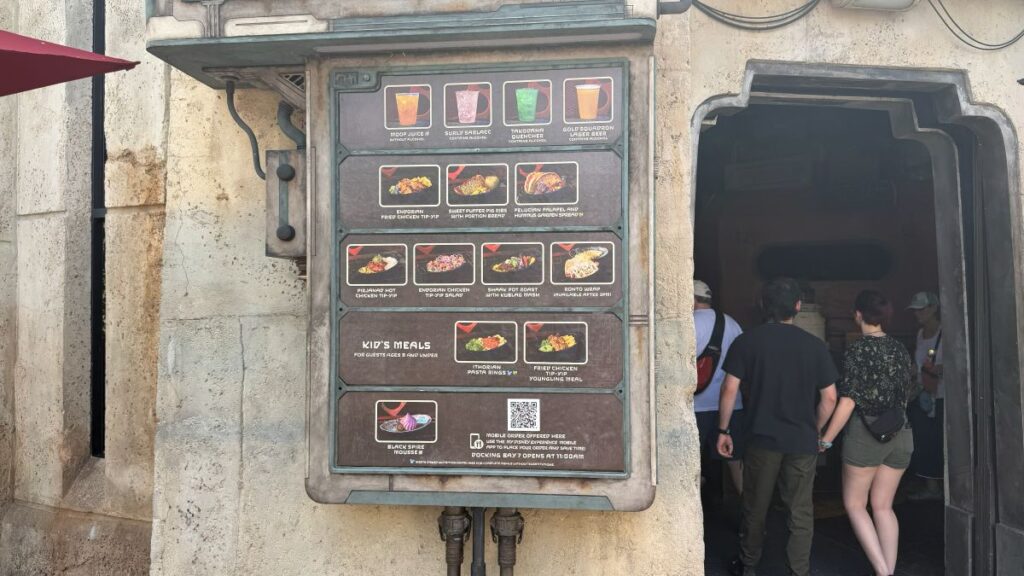 A close-up view of the entrance to Docking Bay 7, showcasing a detailed digital menu board mounted next to the doorway as guests walk inside.