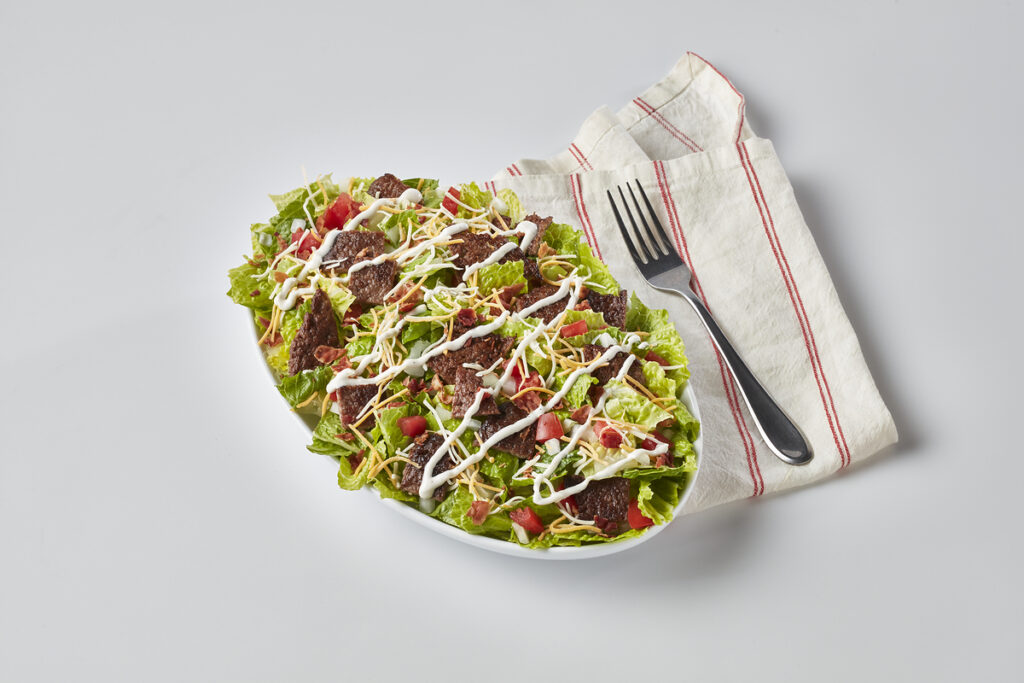 One of Freddy's New Menu Bowls is pictured, the Steakburger Bowl. It is shown next to a fork and napkin.