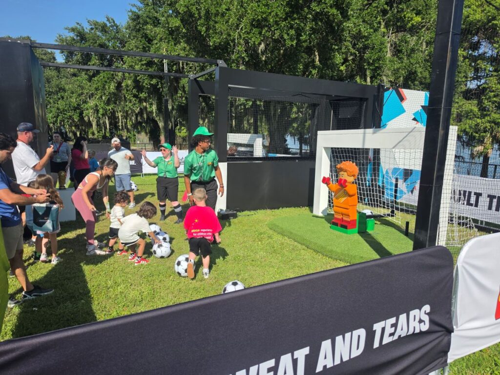 Kids playing at Legoland Florida World Cup activations kicking against a LEGO goalie.