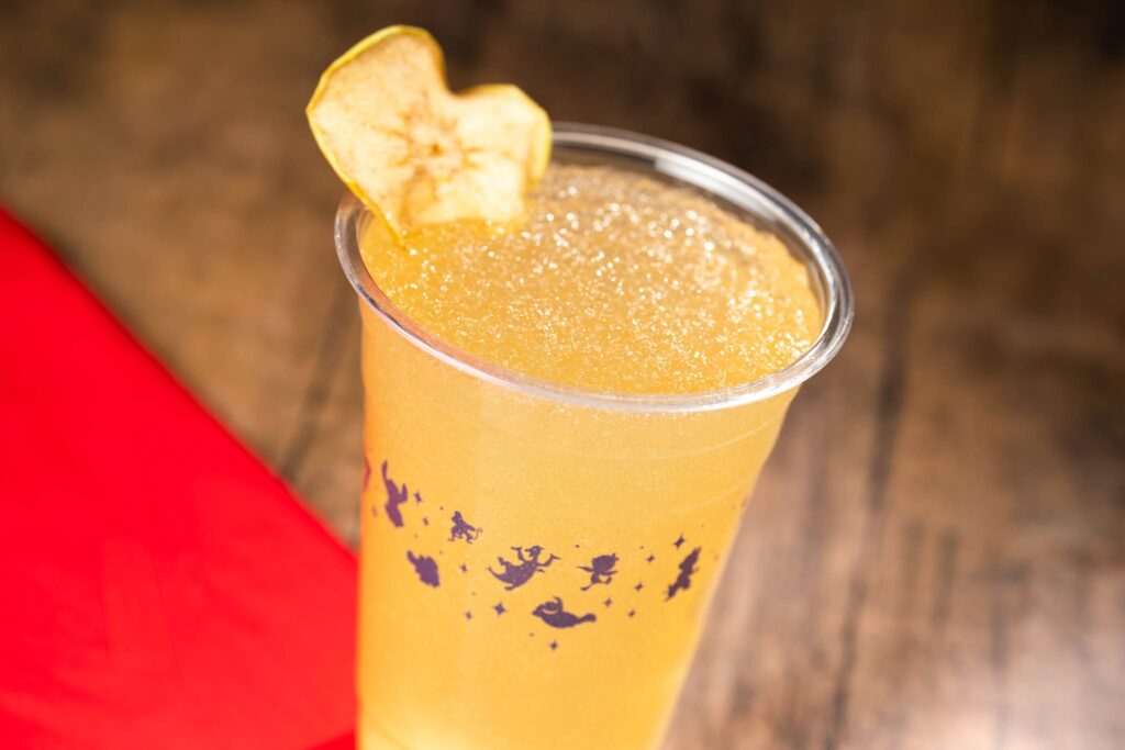 La Poutinerie Epcot Mule beverage- drink shown in plastic cup with a yellow tint