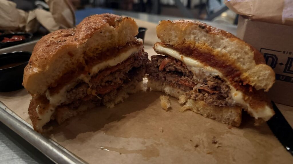 Pepperoni Pizza Burger is seen cut showing off the interior of the burger