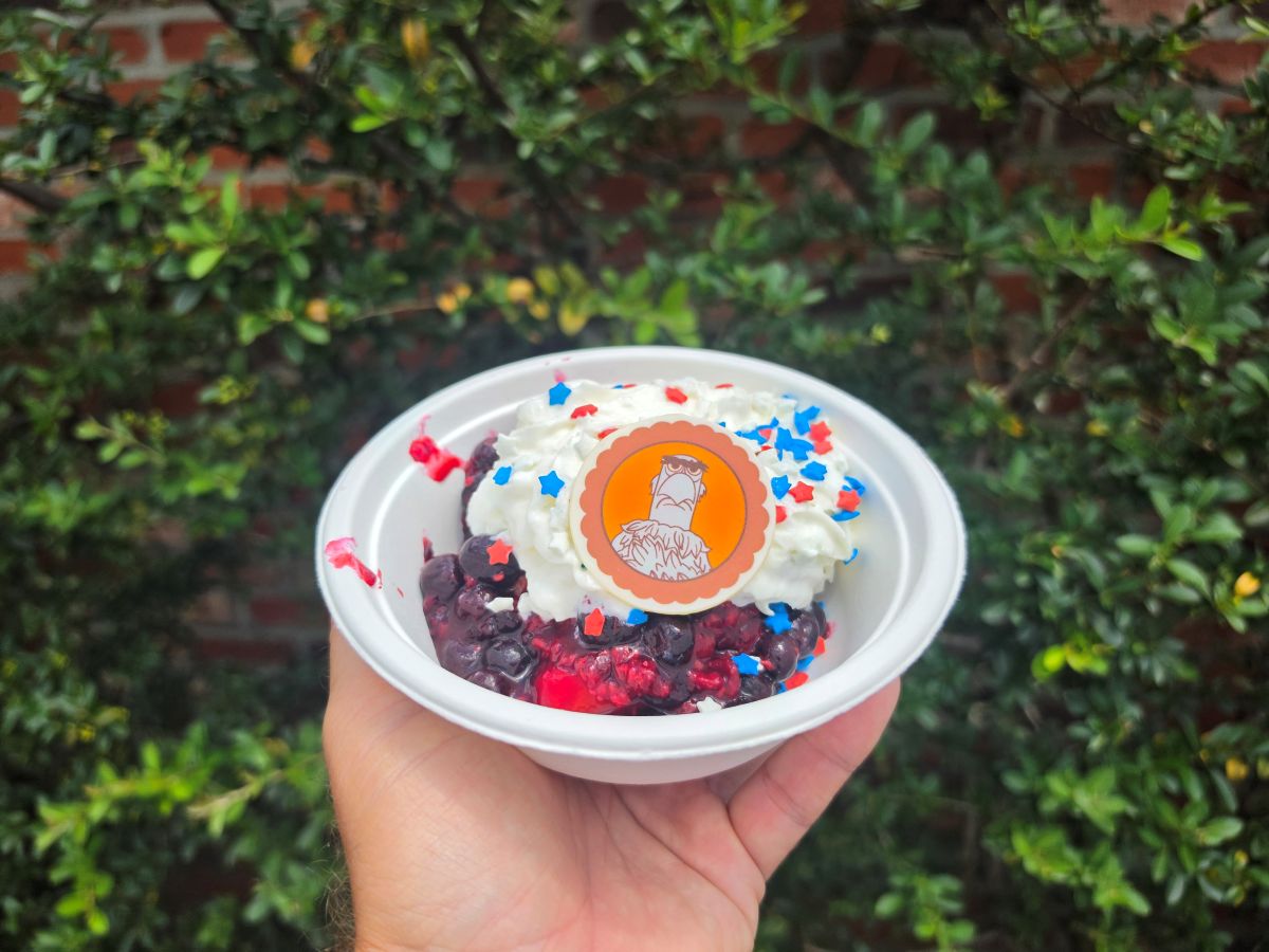 A star-spangled Sam Eagle berry shortcake dessert held up in an outdoor brick patio seating area, showcasing vibrant Fourth of July Treats perfect for a summer celebration.