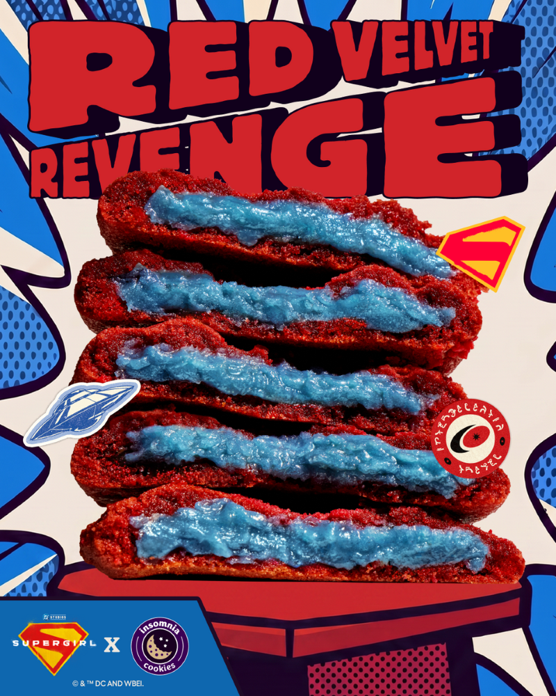 A vertical stack of five halved Red Velvet Revenge cookies from Insomnia Cookies, showcasing a thick, vibrant blue sugar cookie dough filling inside the deep red cookies. The background has a blue and white comic book pop-art style with the text "RED VELVET REVENGE" at the top and the Supergirl and Insomnia Cookies logos at the bottom.