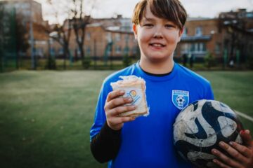 World Cup Food Giveaway image showing a child with a soccer ball and a handheld food item from the World Food Kitchen.