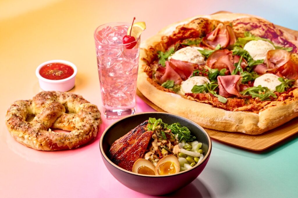 Spread of exclusive food items featured during Universal Orlando Passholder Days including pizza, pretzel, bowl, and cocktail.
