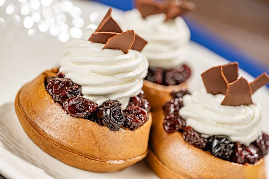 Dark chocolate waffle topped with cherry compote, whipped cream, and chocolate shavings at Ale & Compass breakfast.