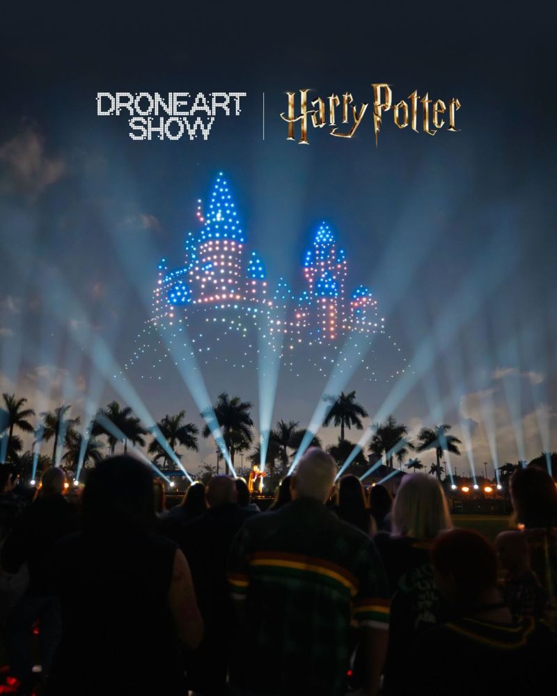 A crowd watching an illuminated Hogwarts castle created by a drone light show at night with spotlights and DroneArt Show Harry Potter text overlay.