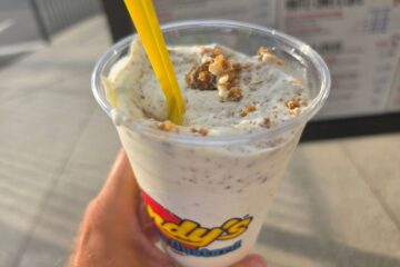 Close-up of a hand holding a Key Lime Pie Concrete from Andy's Frozen Custard, showing thick frozen custard blended with graham cracker crust pieces.