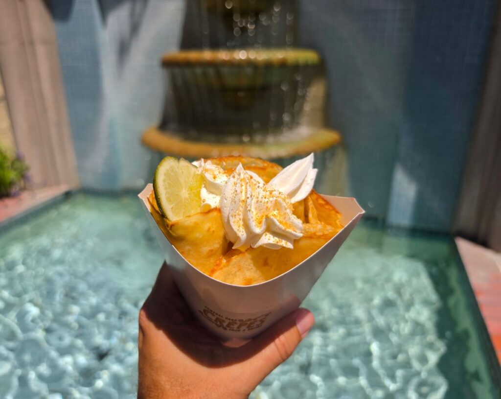 A top-down shot of a Key Lime crepe unwrapped on paper packaging, showing the folded golden dough, white cream filling, and a hint of lime.