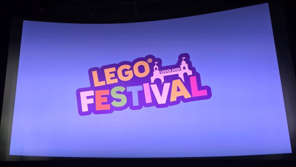 A colorful graphic displayed on a screen showing the "Lego Festival" logo in bold, playful lettering, with the Legoland castle silhouette icon sitting above the text against a light purple background.
