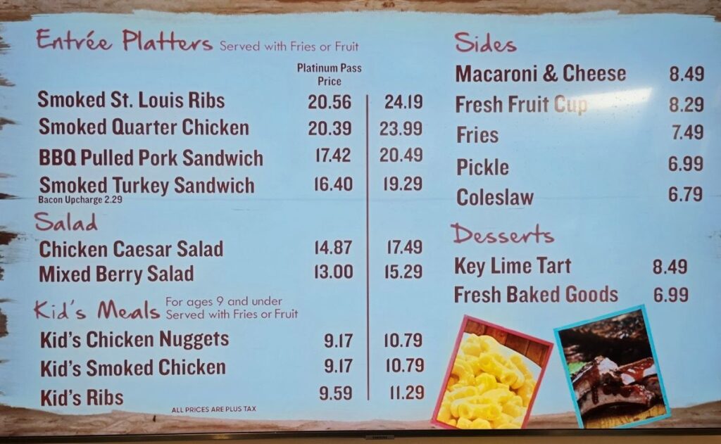 Digital menu board at Mango Joe's Beach Cafe showing prices for entrée platters, salads, sides, and desserts with Platinum Pass discounts.