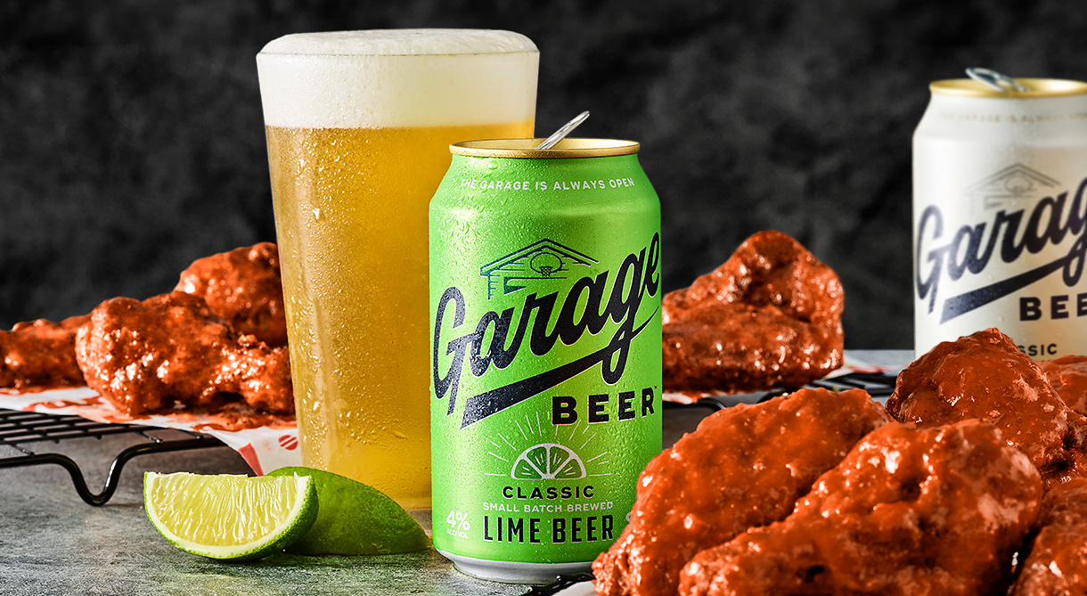 An informal garage atmosphere with various beer bottles and a large plate of chicken wings, perfect for a relaxed get-together for the Red Robin Garage Beer collaboration