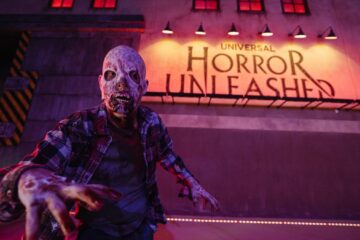 Scareactor zombie reaches toward the camera outside the Universal Horror Unleashed attraction facade promoting Resident Evil Las Vegas.