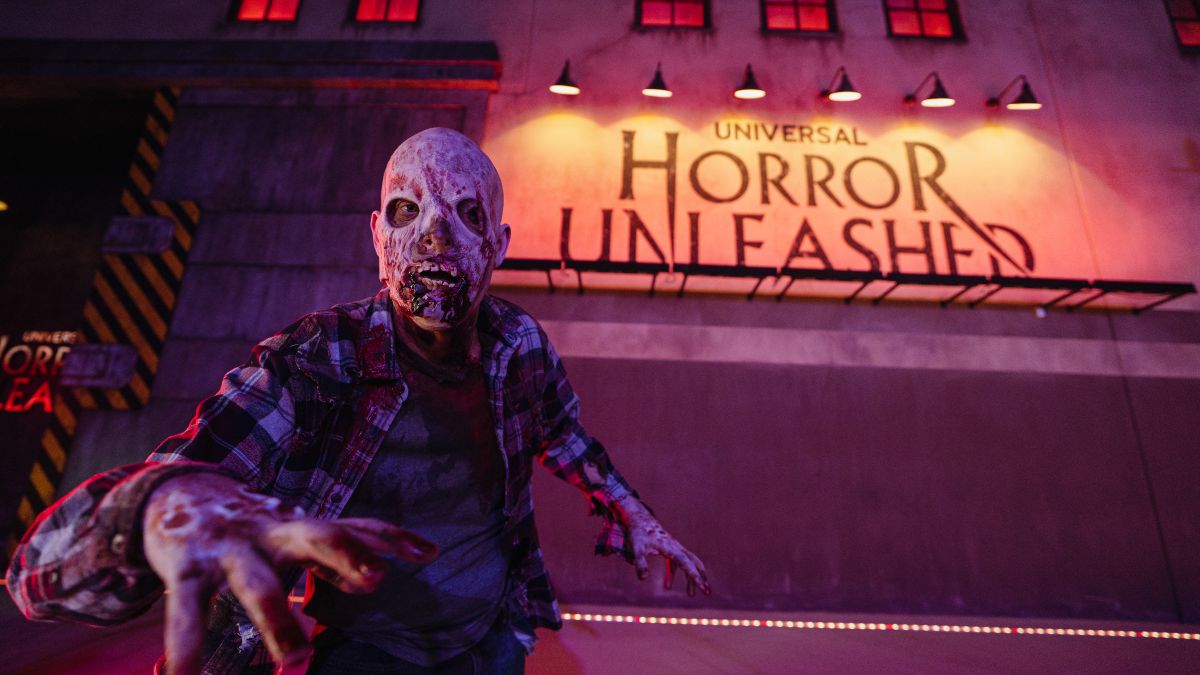 Scareactor zombie reaches toward the camera outside the Universal Horror Unleashed attraction facade promoting Resident Evil Las Vegas.