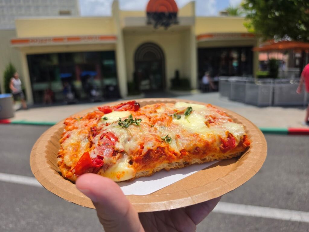 Close-up side profile of a slice of Tomato Mozzarella Flatbread showing the thick, airy crust and melted toppings.