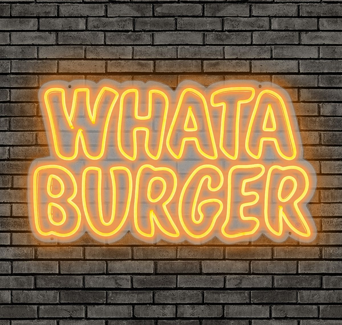 Illuminated yellow and orange Whataburger neon sign mounted on a dark brick wall