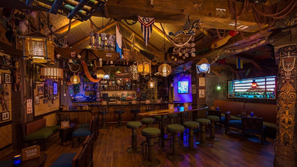 The intricately detailed interior of Trader Sam's Grog Grotto showing wooden beams, tiki carvings, a bar counter, and warm tropical lighting.