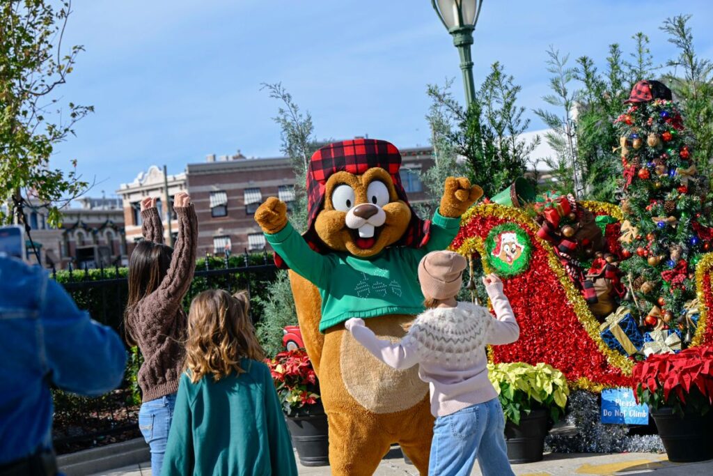 Earl the Squirrel character posing with children near a holiday sleigh decorated for the Universal Orlando holiday season.