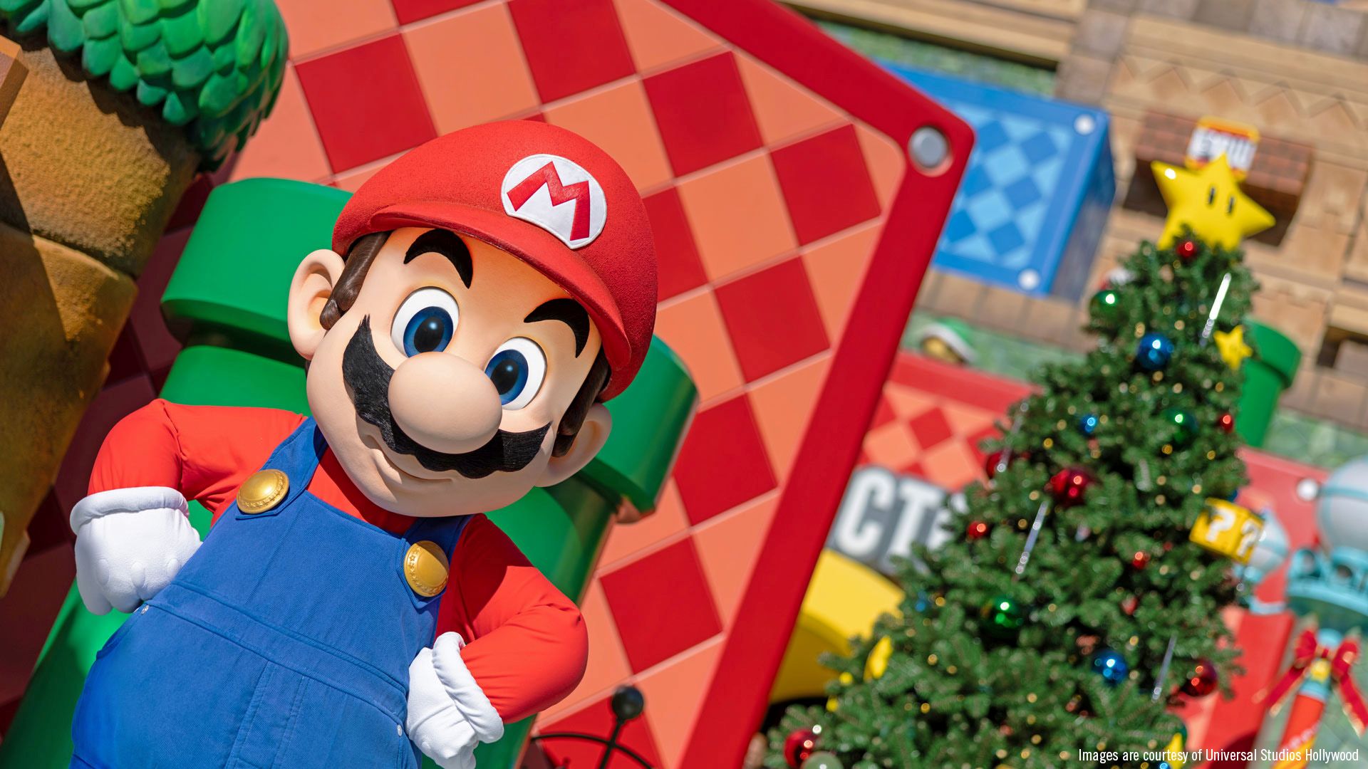 Mario character posing next to a decorated Christmas tree in Super Nintendo World