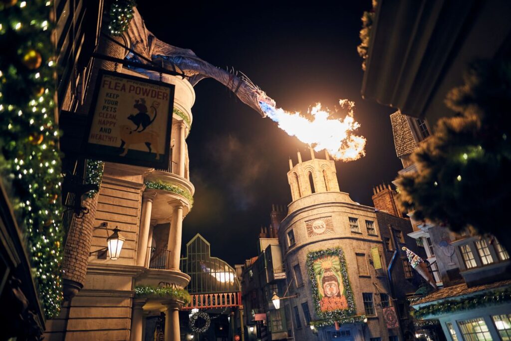 Fire-breathing dragon on Gringotts Bank at night with festive Christmas greenery in Diagon Alley during Universal Orlando holiday season