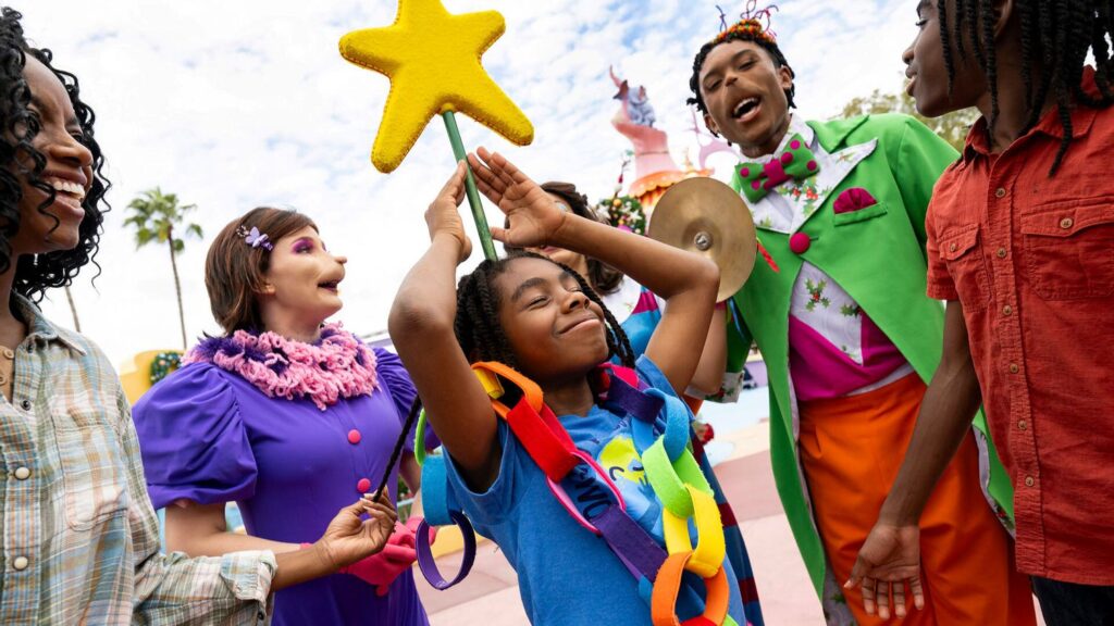 Whos interacting with a child wearing a colorful paper chain during Grinchmas celebrations